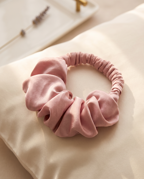 Blush heatless curl scrunchie on a cream silk pillowcase